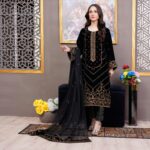 A stylish woman in embroidered Pakistani attire posing indoors.